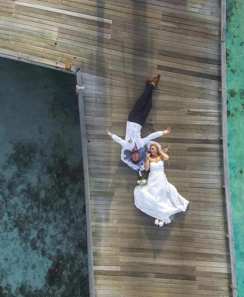Photo of Bride and Groom Laying on Pier